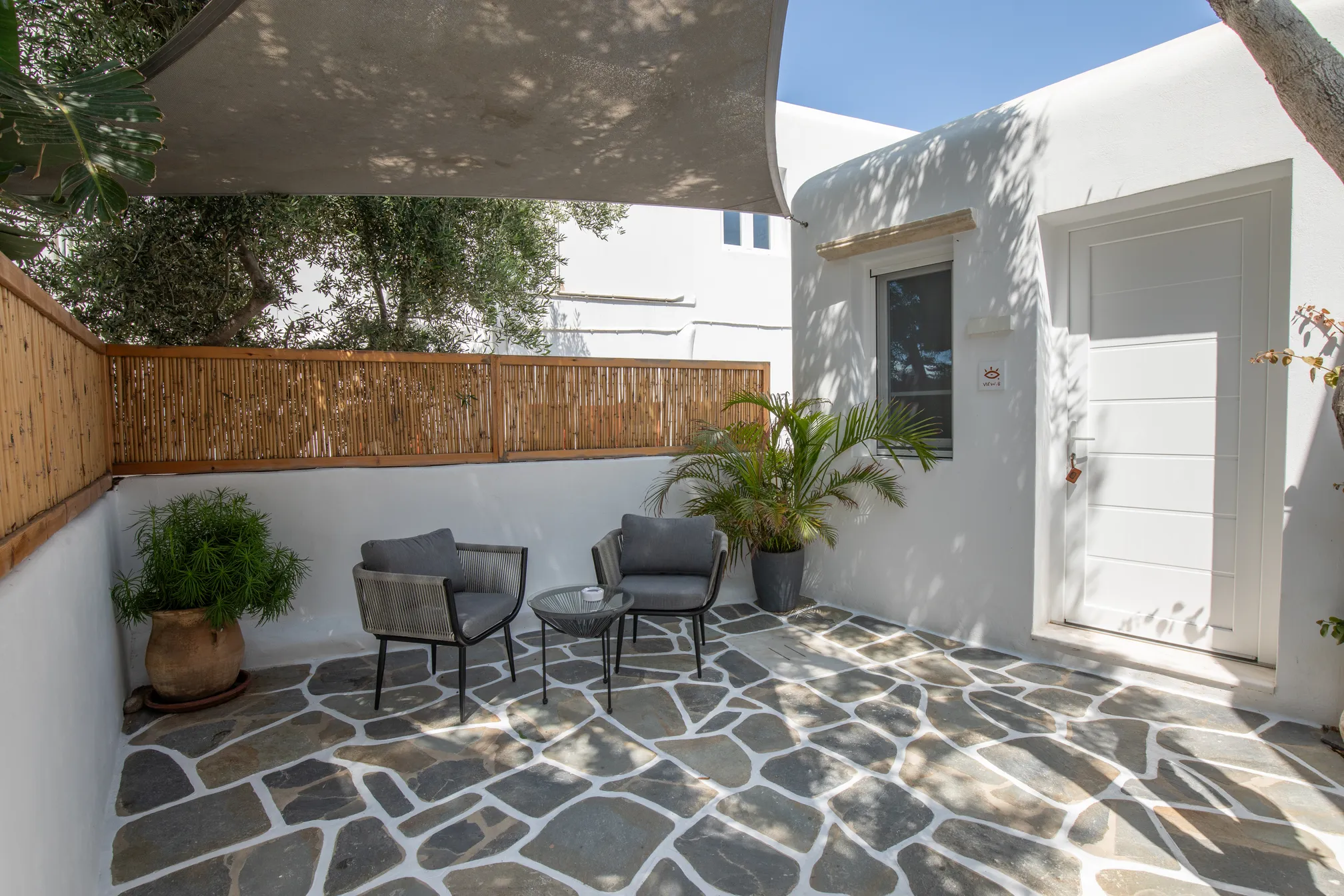 Courtyard with rope armchairs under a shade sail